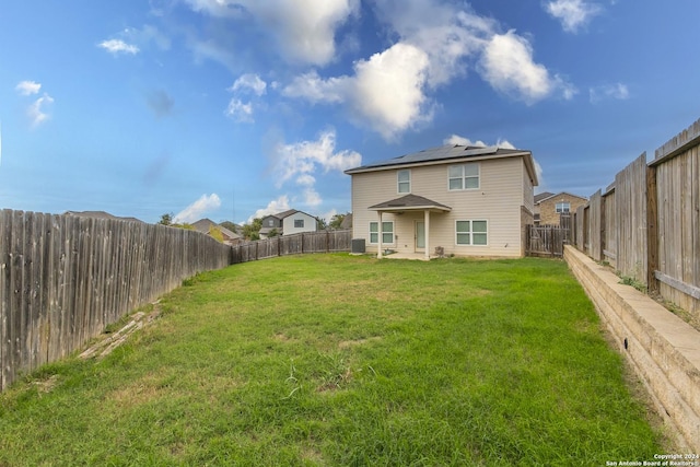 rear view of property with a lawn and solar panels