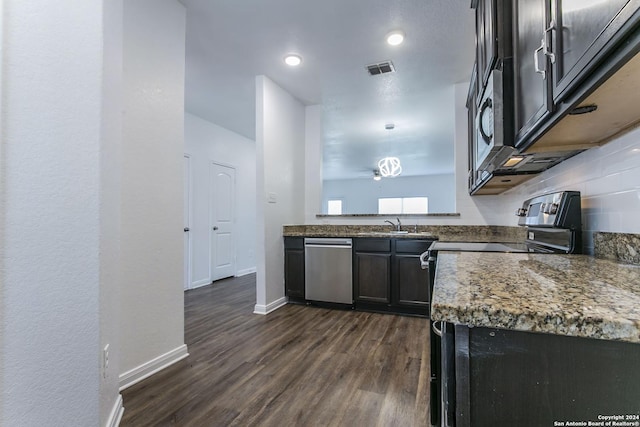 kitchen with backsplash, dark stone counters, stainless steel appliances, sink, and dark hardwood / wood-style floors