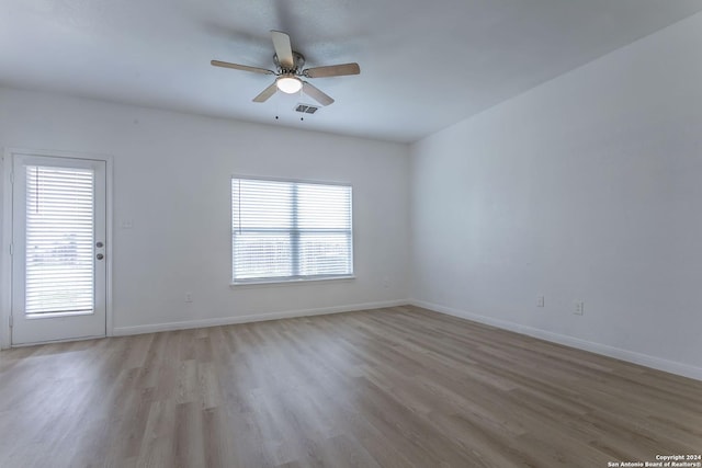 unfurnished room featuring a wealth of natural light, ceiling fan, and light wood-type flooring