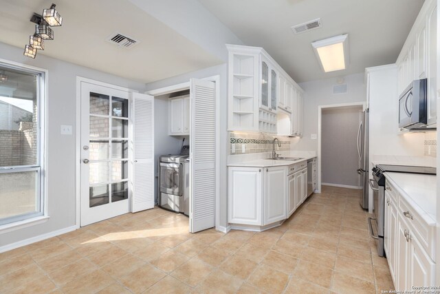 kitchen with appliances with stainless steel finishes, independent washer and dryer, white cabinetry, and sink