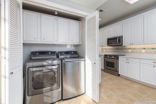 clothes washing area with washing machine and dryer and light tile patterned floors