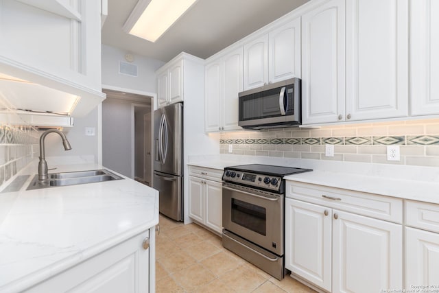 kitchen with sink, light tile patterned flooring, backsplash, white cabinets, and appliances with stainless steel finishes