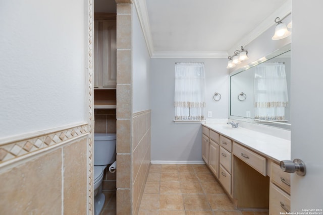 bathroom with a healthy amount of sunlight, crown molding, toilet, vanity, and tile walls