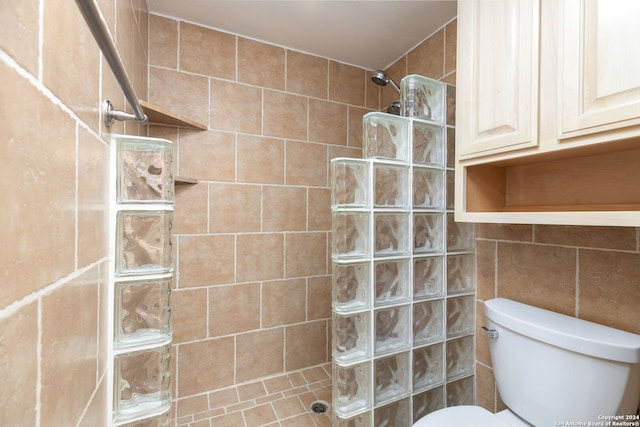 bathroom featuring tile patterned flooring, toilet, tiled shower, and tile walls