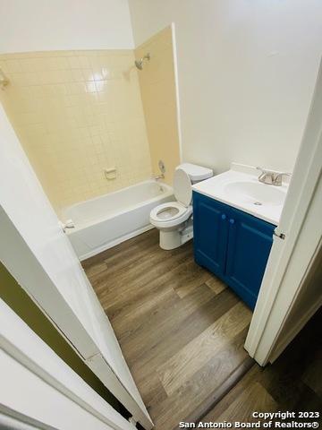 full bathroom with hardwood / wood-style floors, vanity, shower / bath combination, and toilet