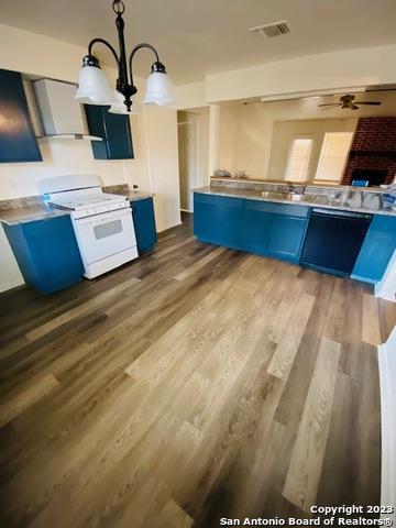 kitchen with blue cabinetry, white stove, hanging light fixtures, and hardwood / wood-style floors