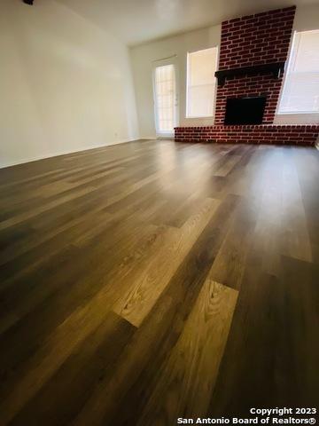 unfurnished living room featuring dark hardwood / wood-style floors and a brick fireplace