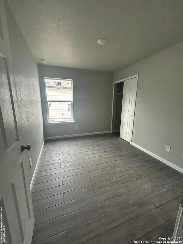 unfurnished bedroom with a closet, dark hardwood / wood-style flooring, and a textured ceiling