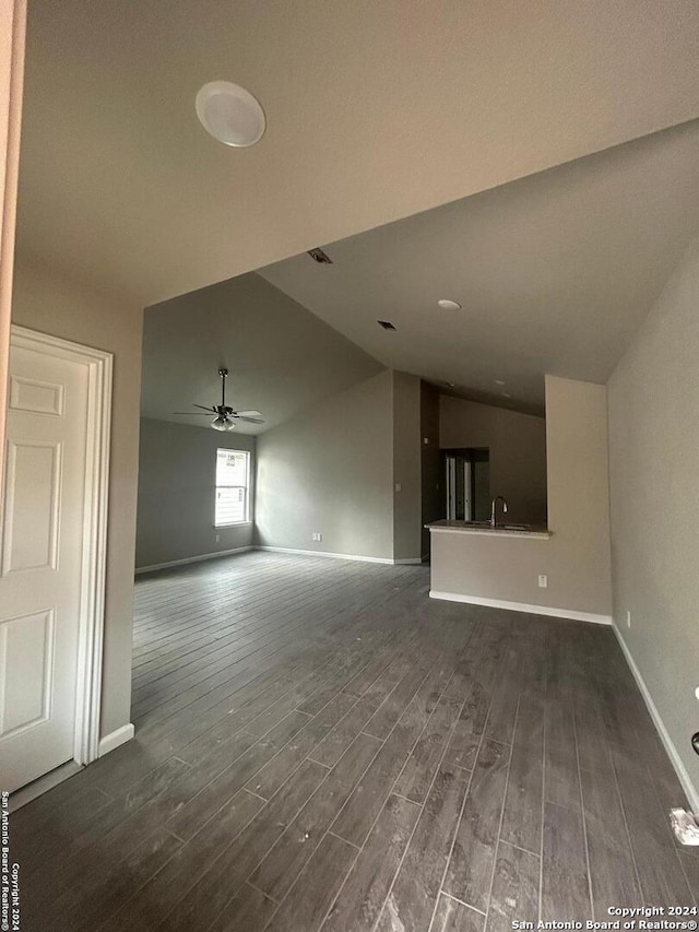 unfurnished living room with ceiling fan, dark hardwood / wood-style flooring, sink, and vaulted ceiling