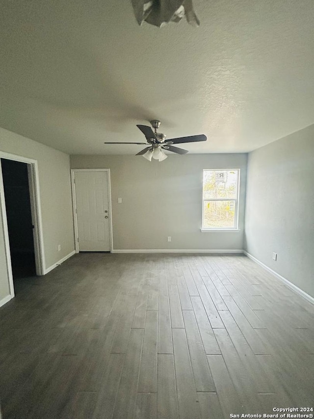 empty room with ceiling fan, wood-type flooring, and a textured ceiling