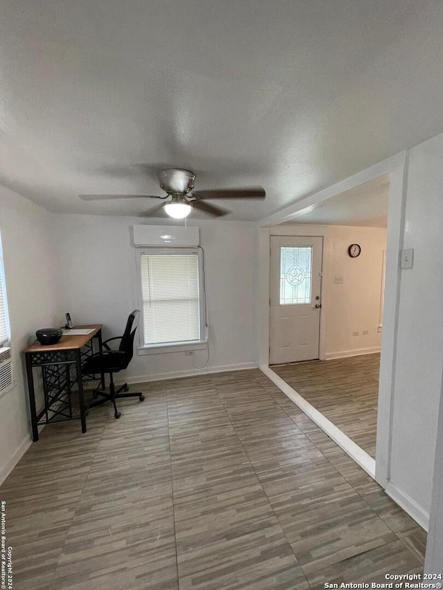 office with a wall unit AC, ceiling fan, hardwood / wood-style floors, and a textured ceiling