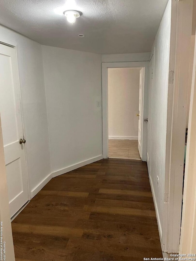 hallway featuring dark hardwood / wood-style flooring and a textured ceiling