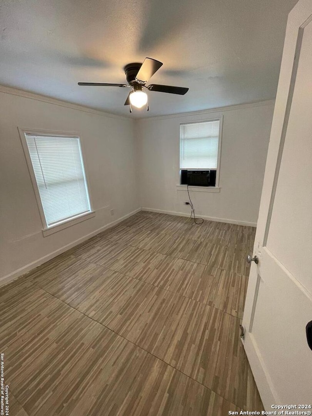 empty room with a textured ceiling, hardwood / wood-style flooring, ceiling fan, and a healthy amount of sunlight