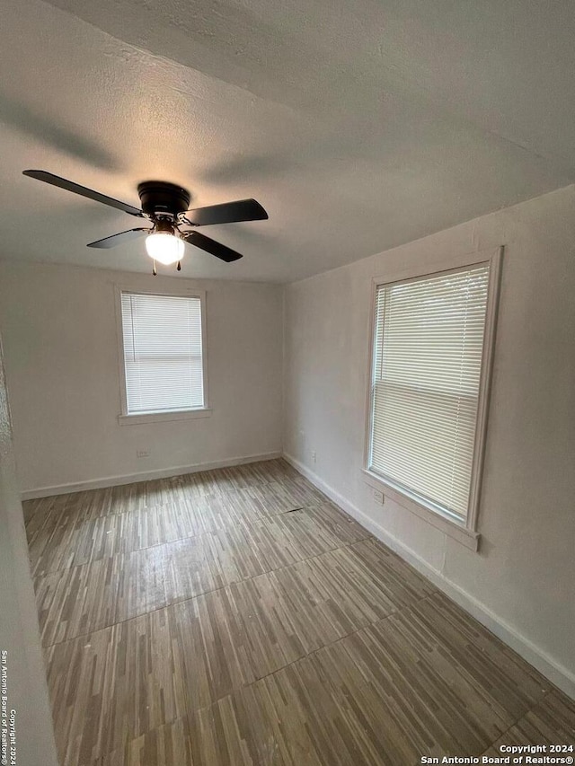 empty room with hardwood / wood-style floors, a textured ceiling, and ceiling fan