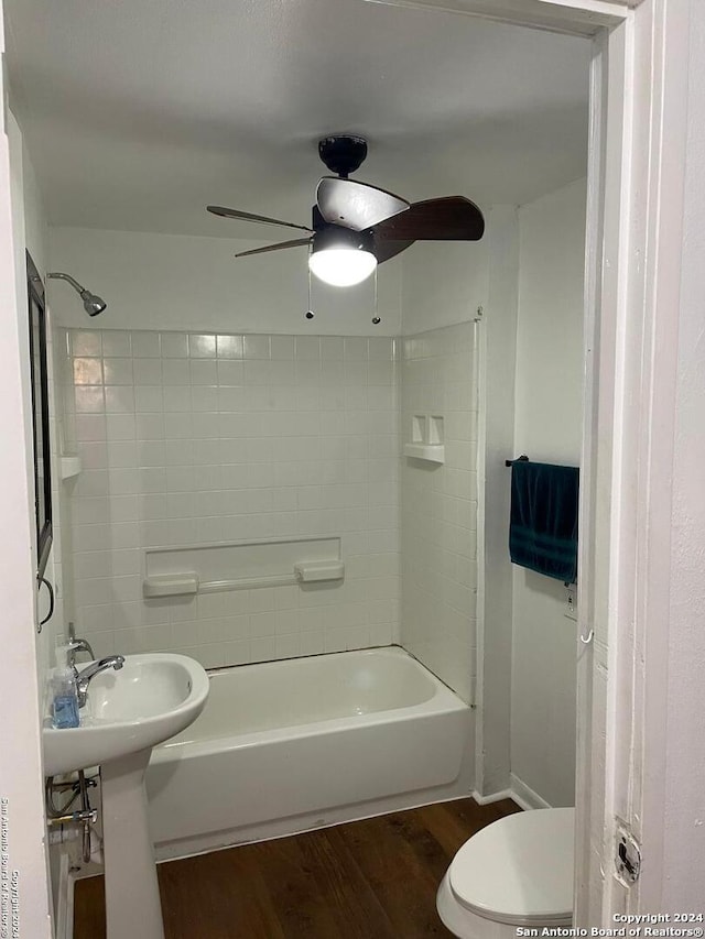 bathroom with wood-type flooring, tiled shower / bath combo, toilet, and ceiling fan