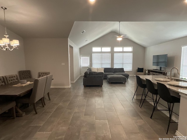 dining area with hardwood / wood-style floors, ceiling fan with notable chandelier, vaulted ceiling, and sink