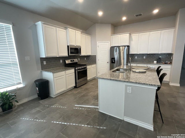 kitchen featuring appliances with stainless steel finishes, white cabinetry, and an island with sink