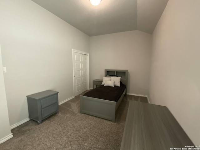 bedroom with a closet, dark carpet, and vaulted ceiling