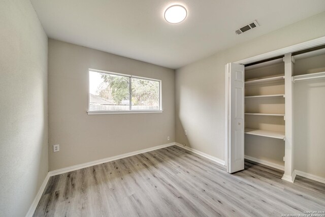 unfurnished bedroom with light hardwood / wood-style flooring and a closet