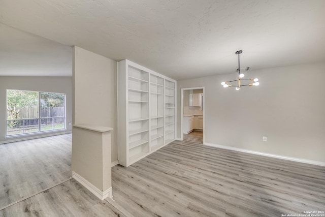 interior space featuring light hardwood / wood-style floors, lofted ceiling, and a notable chandelier