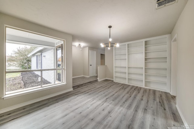 unfurnished dining area with light hardwood / wood-style floors and an inviting chandelier