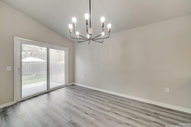 unfurnished dining area featuring a notable chandelier, vaulted ceiling, and light wood-type flooring