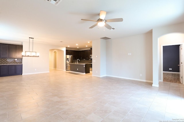 unfurnished living room with ceiling fan, sink, and light tile patterned flooring