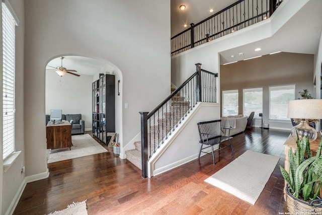 entryway featuring hardwood / wood-style floors, ceiling fan, and a towering ceiling