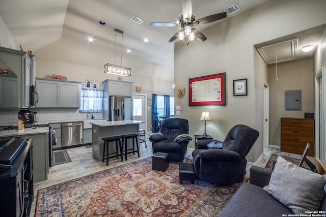 living room with electric panel, ceiling fan, light hardwood / wood-style flooring, and high vaulted ceiling