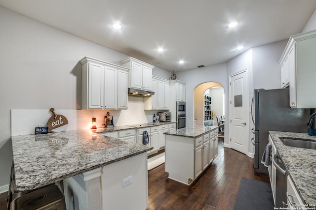 kitchen featuring a center island, light stone countertops, dark hardwood / wood-style flooring, white cabinetry, and a breakfast bar area