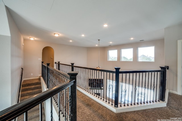 corridor featuring a chandelier and dark carpet