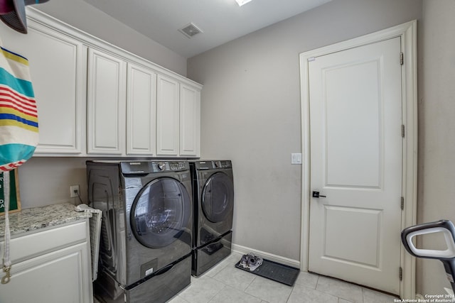 laundry area featuring separate washer and dryer, light tile patterned floors, and cabinets