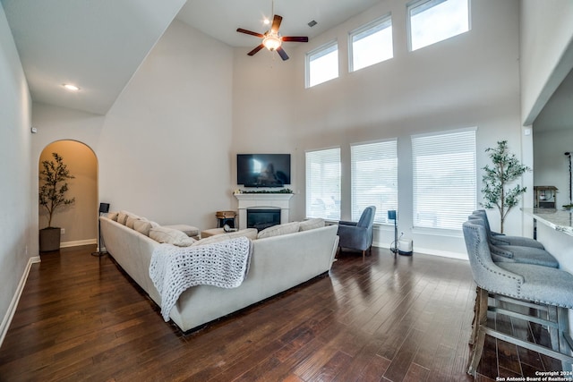 living room featuring a wealth of natural light, high vaulted ceiling, dark wood-type flooring, and ceiling fan