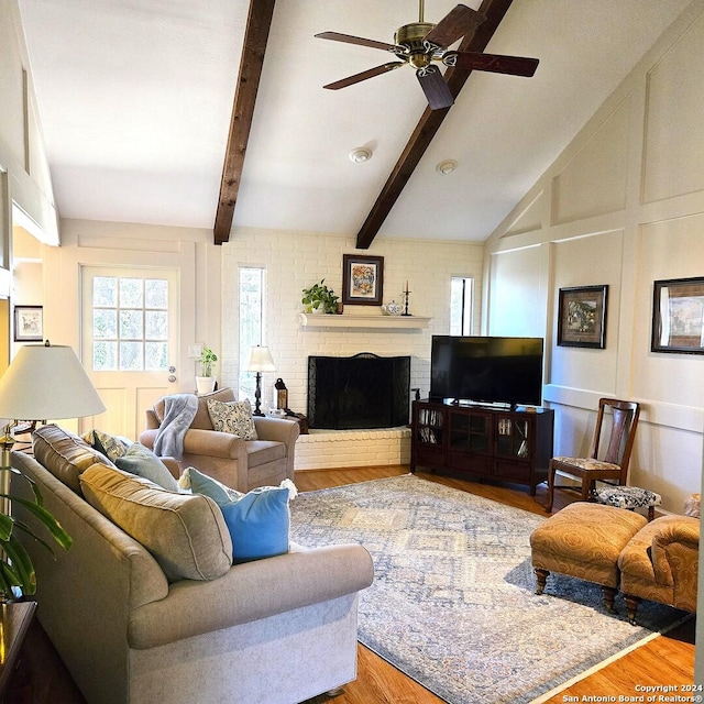 living room with hardwood / wood-style floors, ceiling fan, vaulted ceiling with beams, and a fireplace