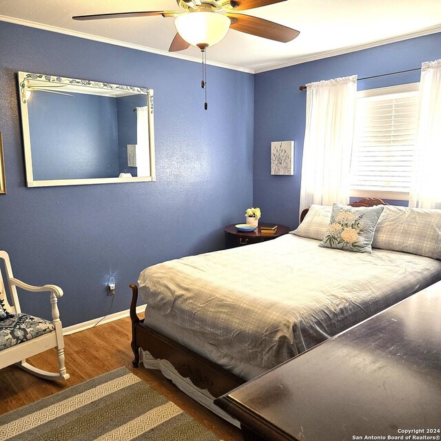 bedroom featuring hardwood / wood-style flooring, ceiling fan, and crown molding