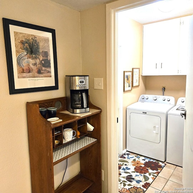 clothes washing area with washer and dryer, cabinets, and light tile patterned floors