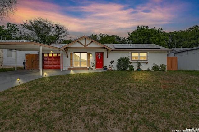 single story home with solar panels, a carport, and a lawn