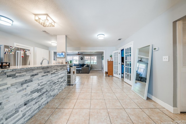 hallway with light tile patterned floors, a textured ceiling, and french doors