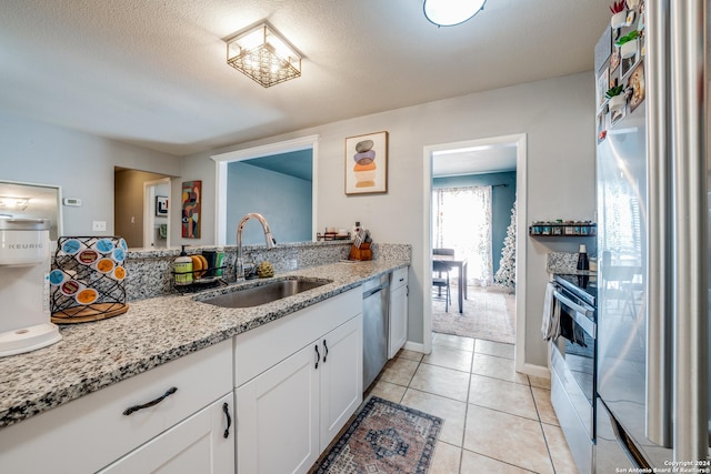 kitchen with light stone counters, sink, white cabinets, and stainless steel appliances