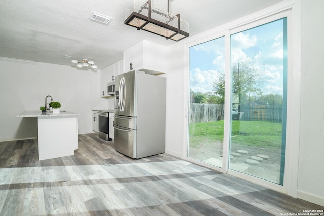 kitchen featuring light stone counters, white cabinets, light hardwood / wood-style floors, and appliances with stainless steel finishes