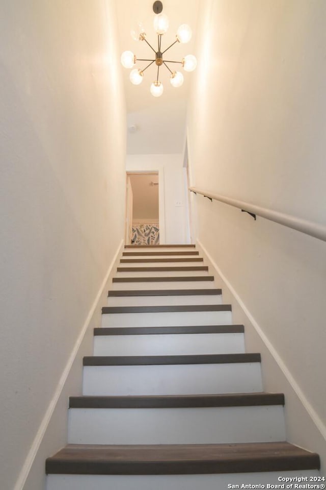 stairway featuring a chandelier