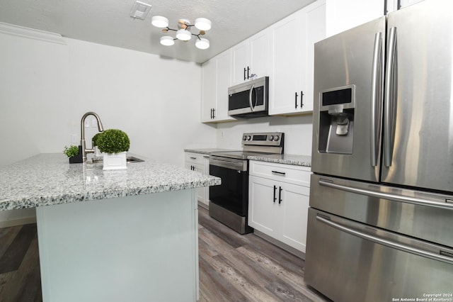 kitchen featuring light stone countertops, white cabinetry, stainless steel appliances, a center island with sink, and hardwood / wood-style flooring