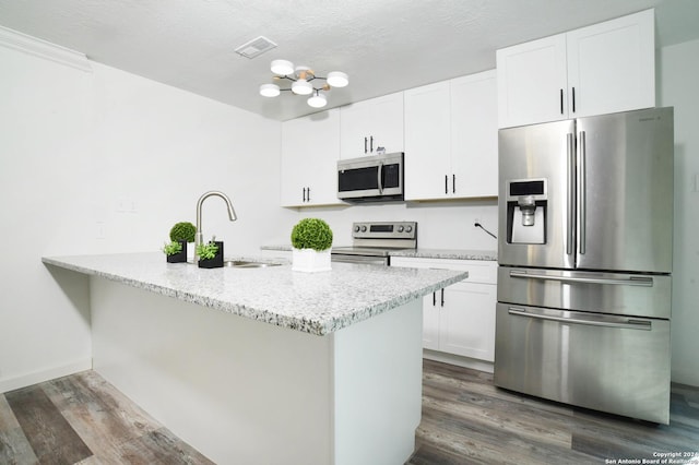 kitchen with dark wood-type flooring, white cabinets, sink, light stone counters, and stainless steel appliances