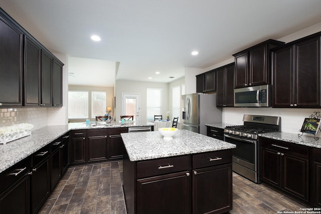 kitchen featuring decorative backsplash, kitchen peninsula, stainless steel appliances, and dark wood-type flooring