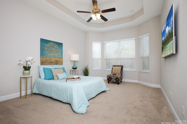 bedroom featuring light carpet, a raised ceiling, and ceiling fan