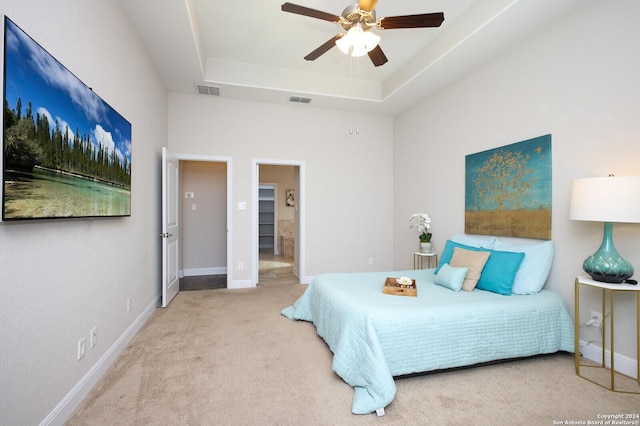 carpeted bedroom with a tray ceiling and ceiling fan