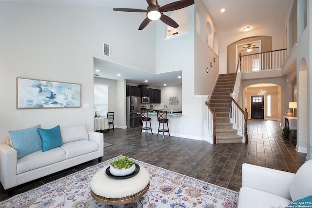 living room featuring a high ceiling, dark wood-type flooring, and a healthy amount of sunlight