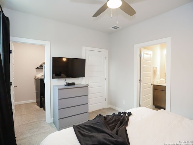 bedroom with light carpet, a closet, ensuite bathroom, and ceiling fan