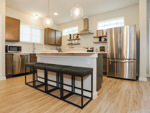 kitchen with a center island, stainless steel appliances, a wealth of natural light, and wall chimney range hood