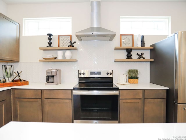 kitchen featuring backsplash, a wealth of natural light, stainless steel appliances, and wall chimney range hood